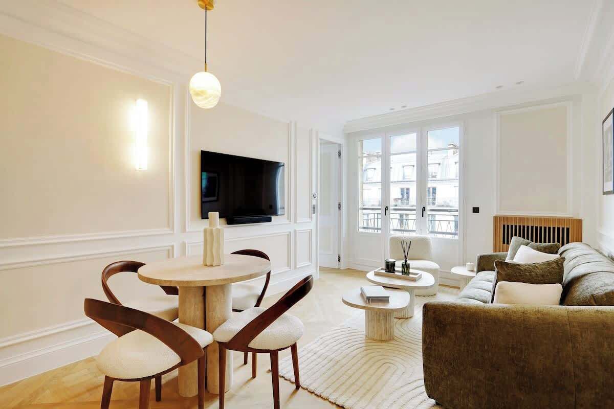 A modern living room with a dining area, a sofa, and a television.