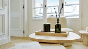 Un salon moderne avec une table basse ronde, un livre et deux vases posés sur un tapis beige.