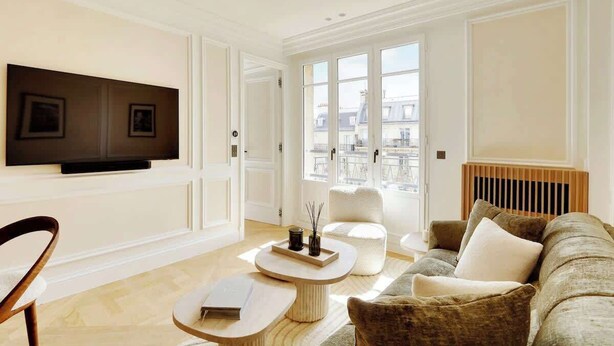 Un salon moderne avec un téléviseur à écran plat fixé au mur, un canapé, une table basse et un fauteuil.