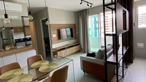 A modern living space with a dining area, sofa, and built-in shelving. - Edifício Promenade II Apt 404 (Maceió)