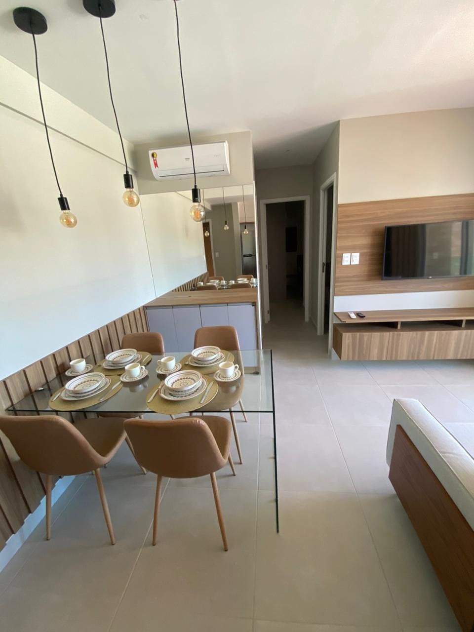 Cocina moderna con comedor, que cuenta con una isla central, iluminación colgante y un televisor integrado.