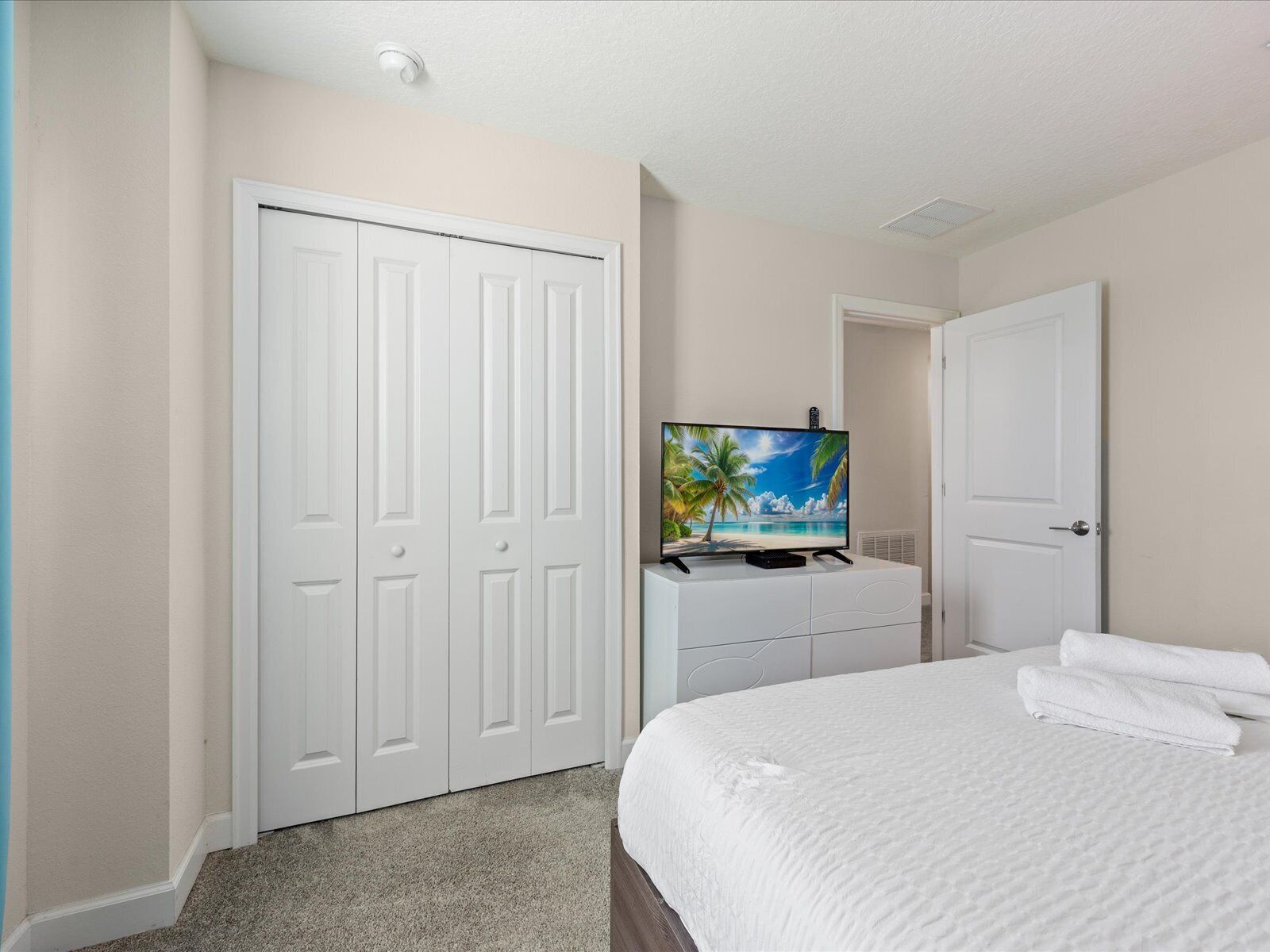 Une chambre d’hôtel avec un lit, un téléviseur posé sur une commode et un placard.