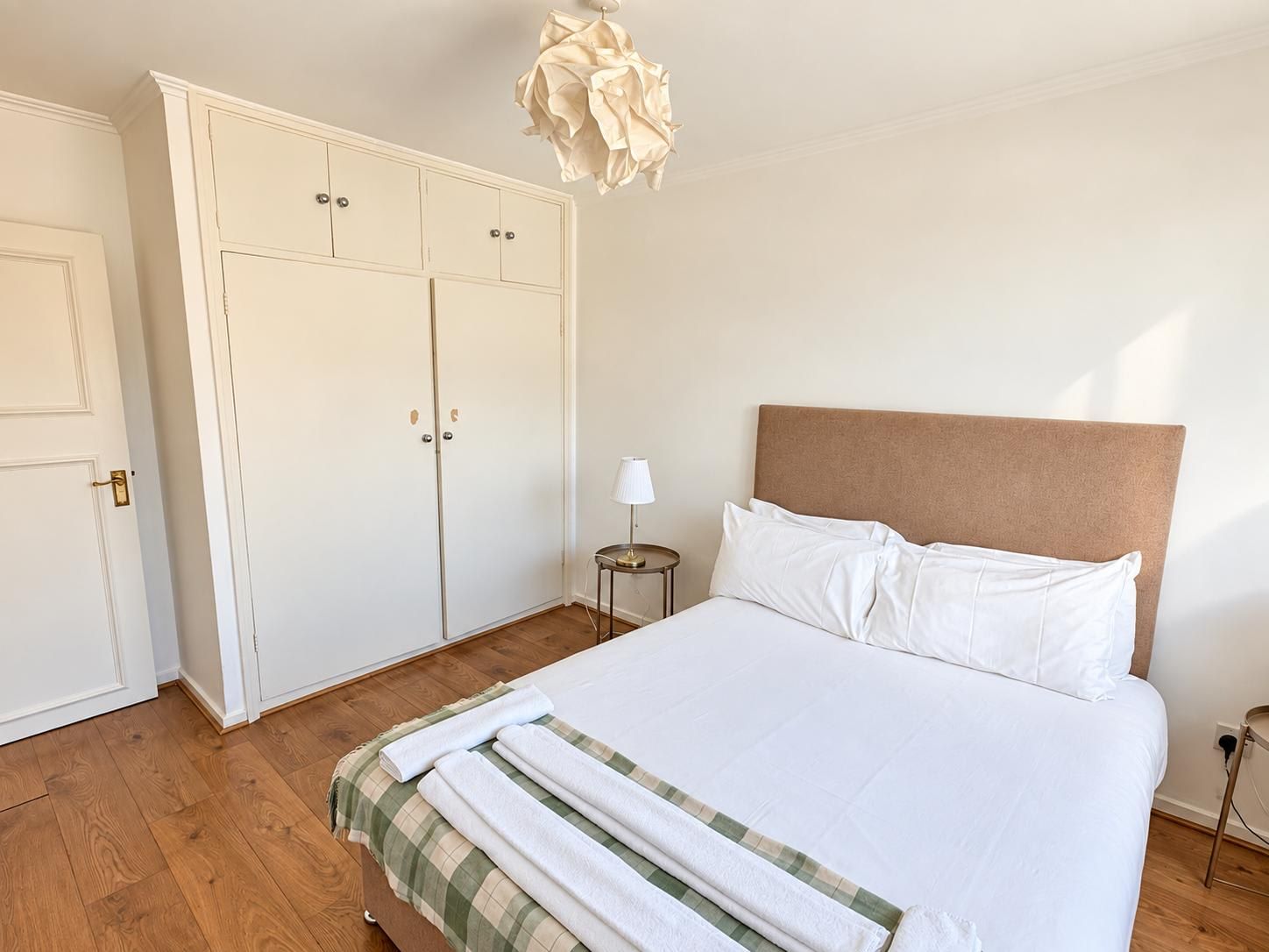 A bedroom with a bed, a wardrobe, a bedside table, and a hanging light fixture.