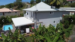 Ein zweistöckiges Haus mit weißem Dach, einem Schwimmbad und einer überdachten Terrasse.