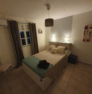 Cozy retreat with a comfortable bed, bedside table, and wall-mounted artwork.