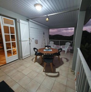 Enjoy al fresco dining in this serene outdoor space with a table for four and a door leading to a cozy interior.