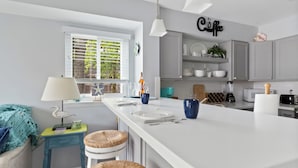 Une cuisine moderne avec un îlot central, des meubles gris et un panneau indiquant « Café ».