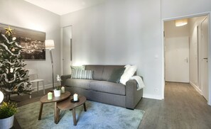 A modern living room with a grey sofa, a small coffee table, and a Christmas tree. - Appartement 2 Chambres, 2 sdb Paris II -ème Centre (Paris)