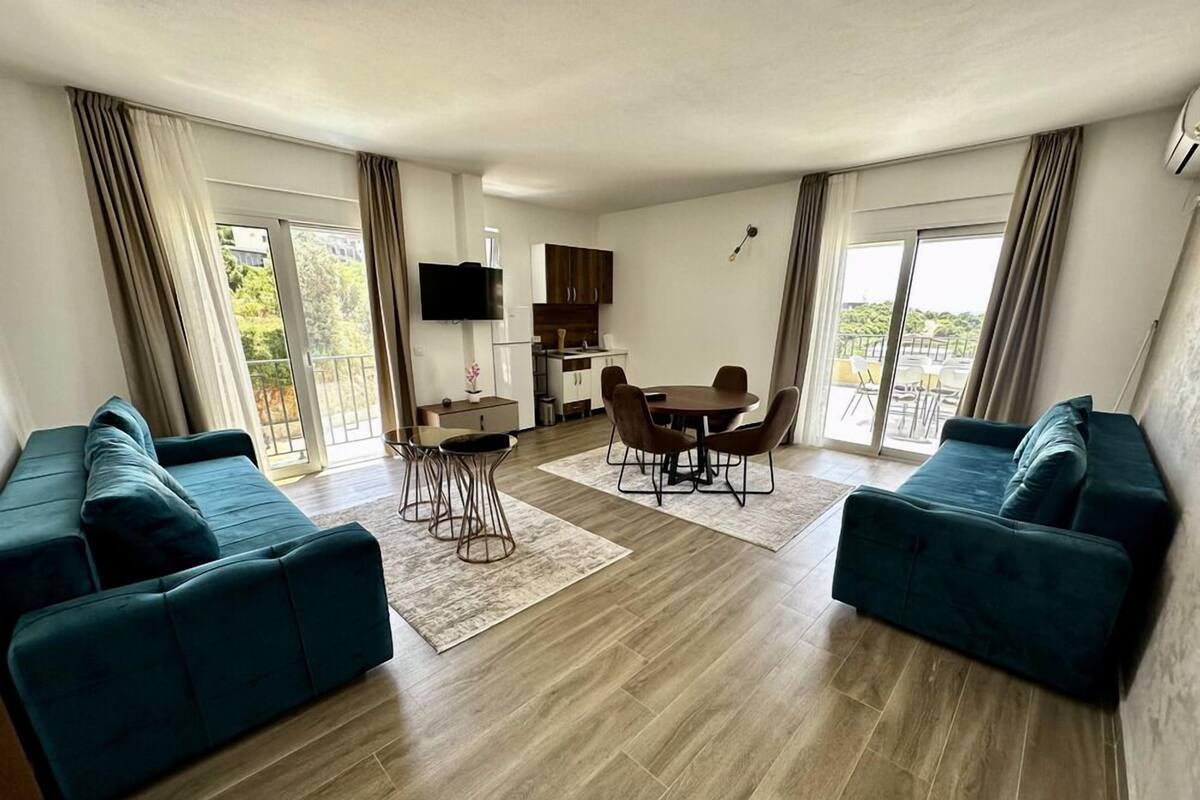 A modern living room with two sofas, a dining table, and a kitchen area.
