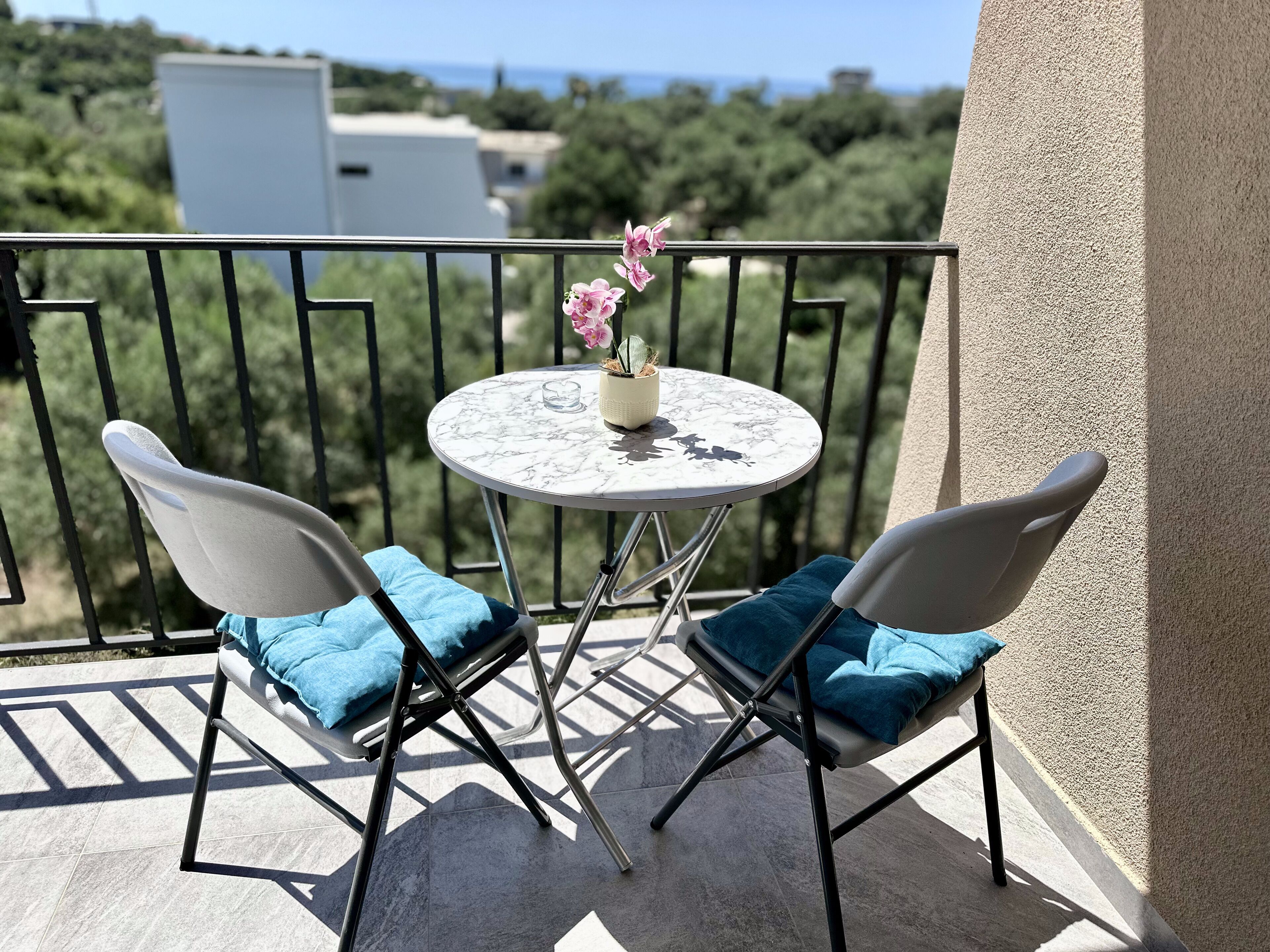 A balcony with two chairs, a small table, and a potted plant.