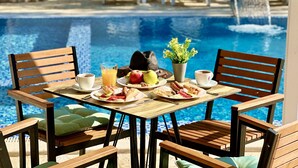 A dining table with chairs and a pool in the background. - Akhdar Apartments (Utjeha)