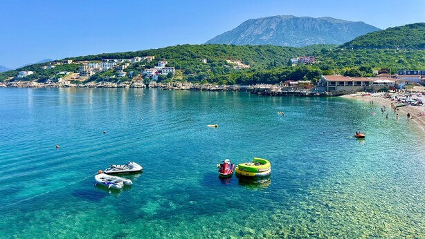 A coastal town with clear waters, boats, and buildings on a hillside. - Akhdar Apartments (Utjeha)