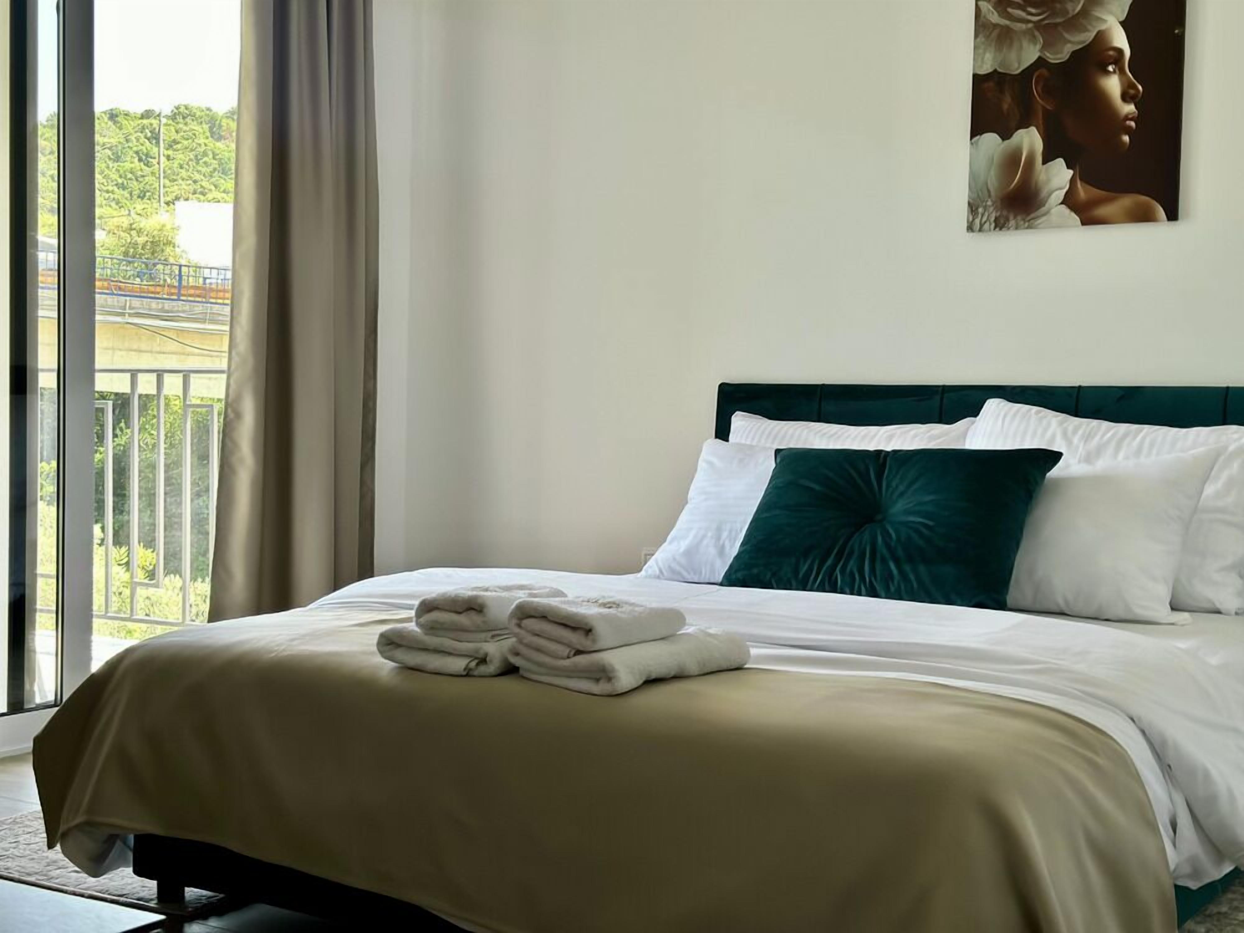 Ein Hotelzimmer mit Bett, Blick auf Grünfläche und einem Bild an der Wand.