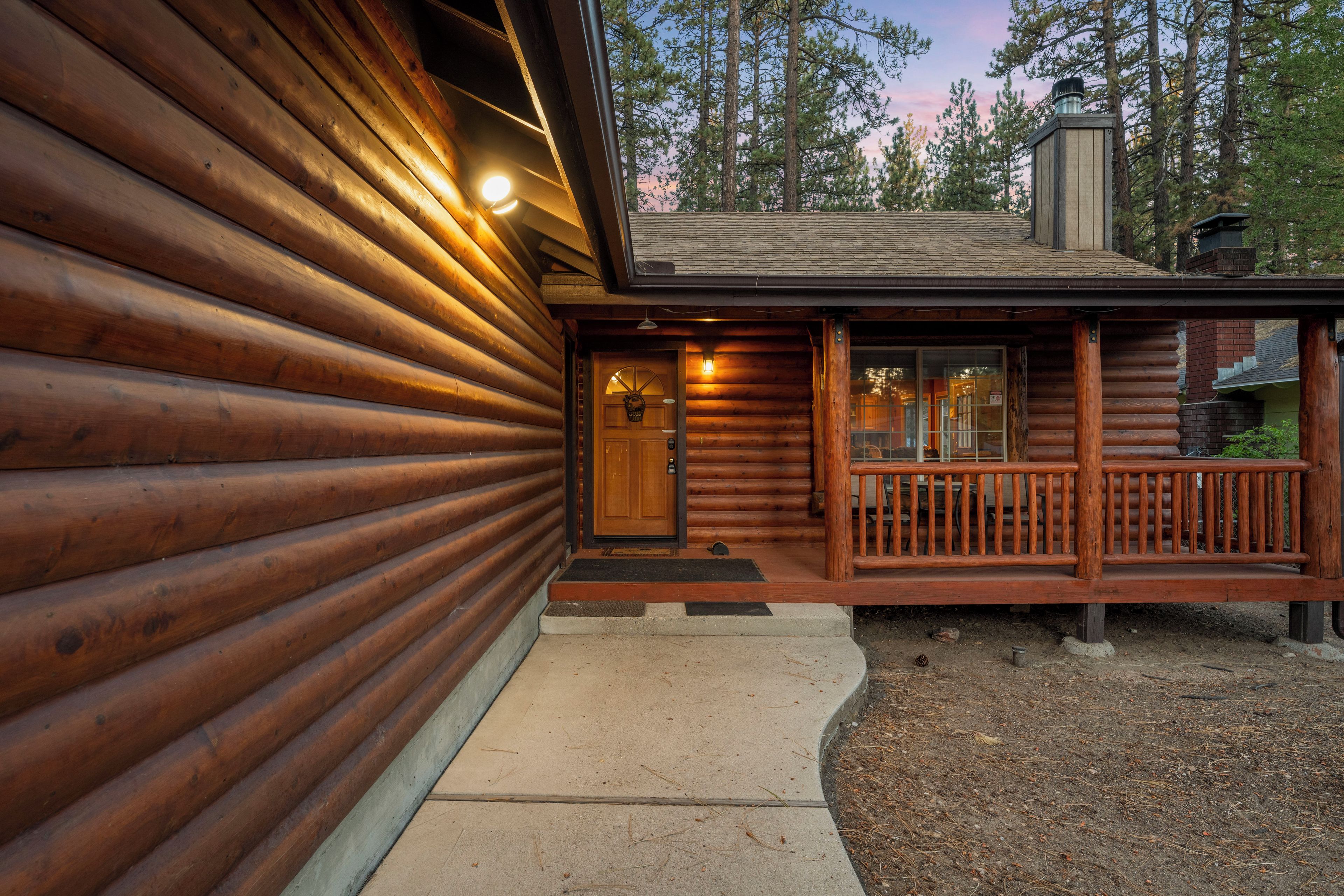A log cabin with a wooden exterior, a front porch, and a chimney.