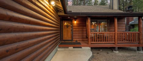 A log cabin with a wooden exterior, a front porch, and a chimney.