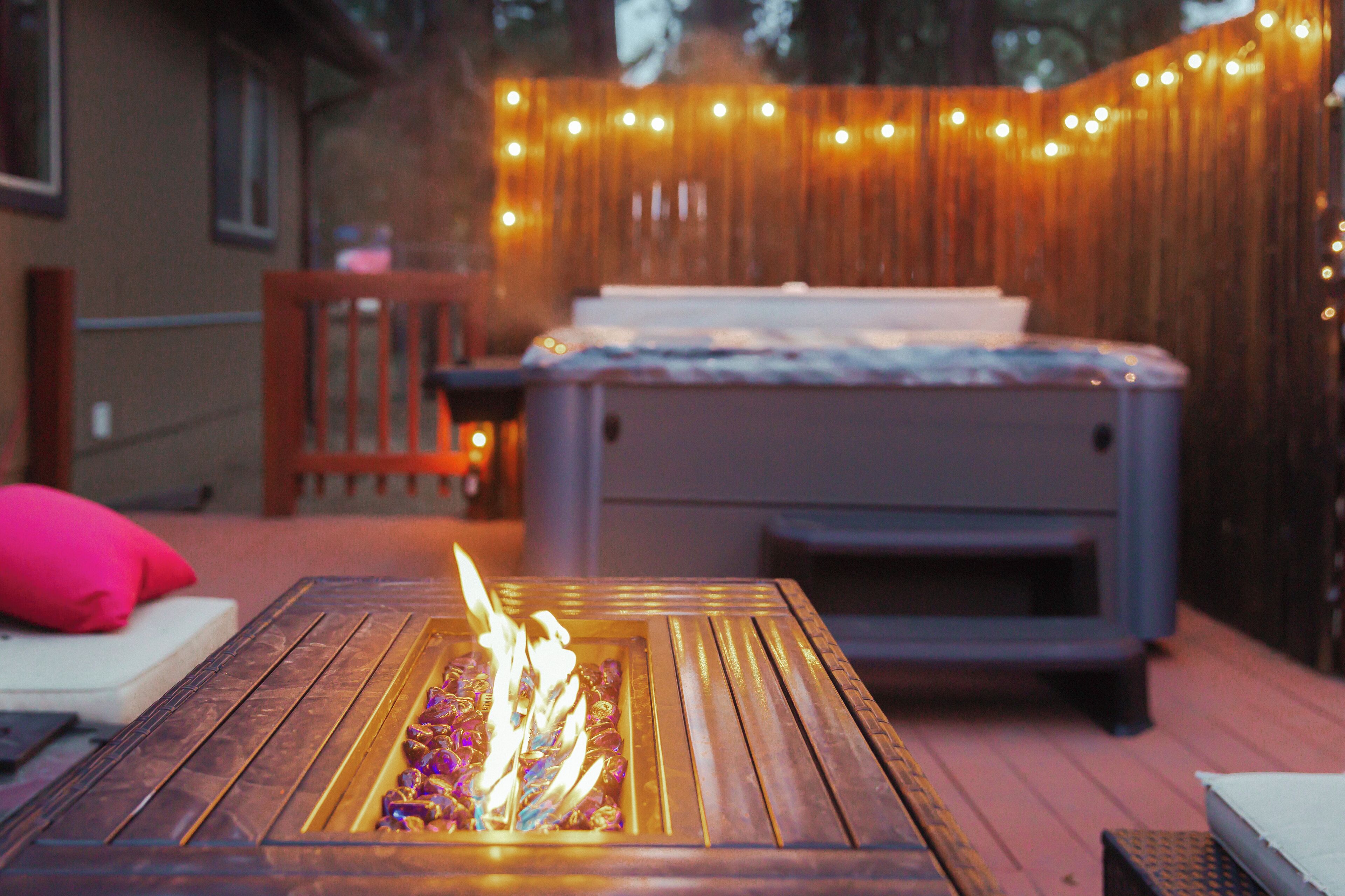 Een houten terras met vuurkorf, zitplaatsen en een hottub.