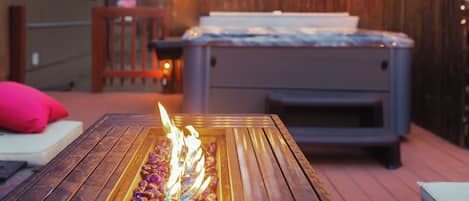 A wooden deck with a fire pit, outdoor seating, and a hot tub.
