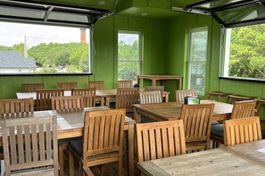 A room with green walls, wooden tables and chairs, and large windows.