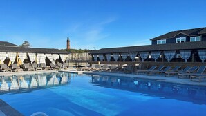 Piscina com espreguiçadeiras e um edifício ao fundo.