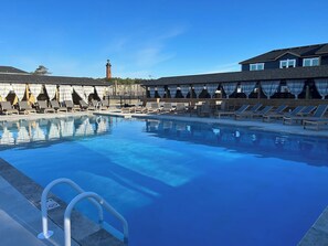 A swimming pool with lounge chairs and a building in the background. - Wave After Wave | Dogs OK, Walk to Beach, Pool (Corolla)