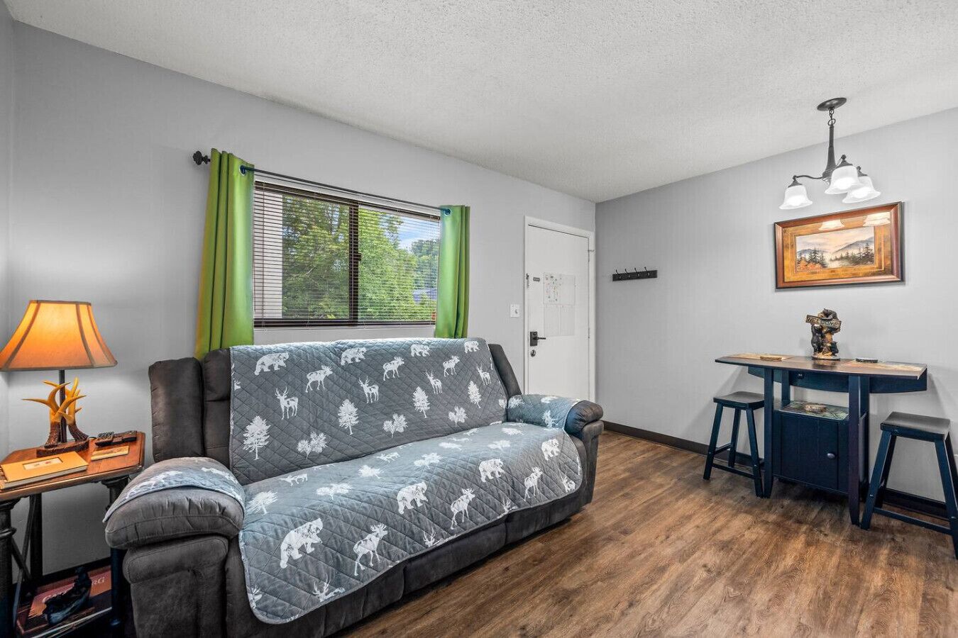 A compact living space with a sofa, a small table, a lamp, and a painting on the wall.