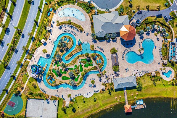 Vue aérienne d’un complexe hôtelier doté de plusieurs piscines, d’un toboggan aquatique et d’un terrain de basketball.