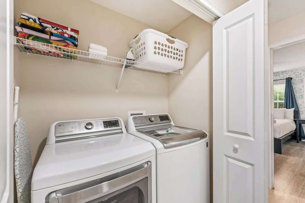 Un espace buanderie comprenant deux machines à laver, une étagère avec des serviettes pliées et un panier à linge.