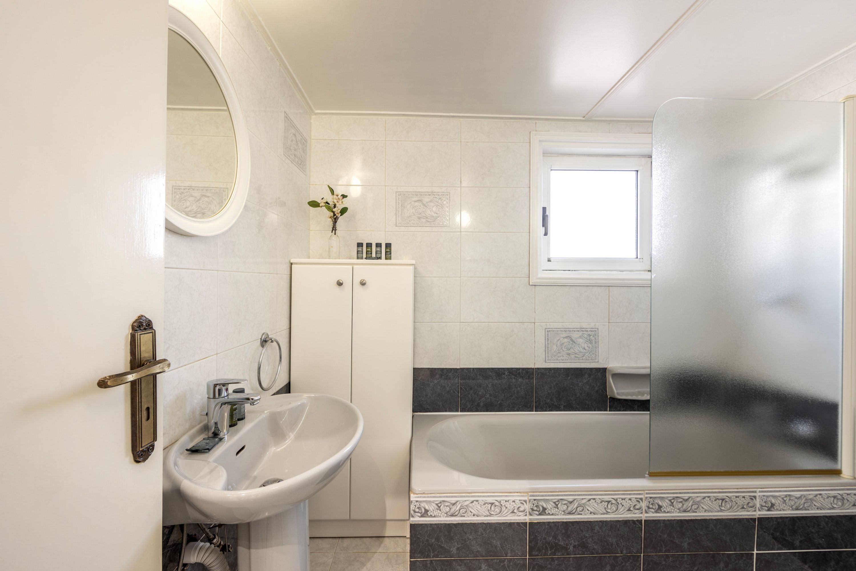 A bathroom with a sink, mirror, cabinet, and bathtub.