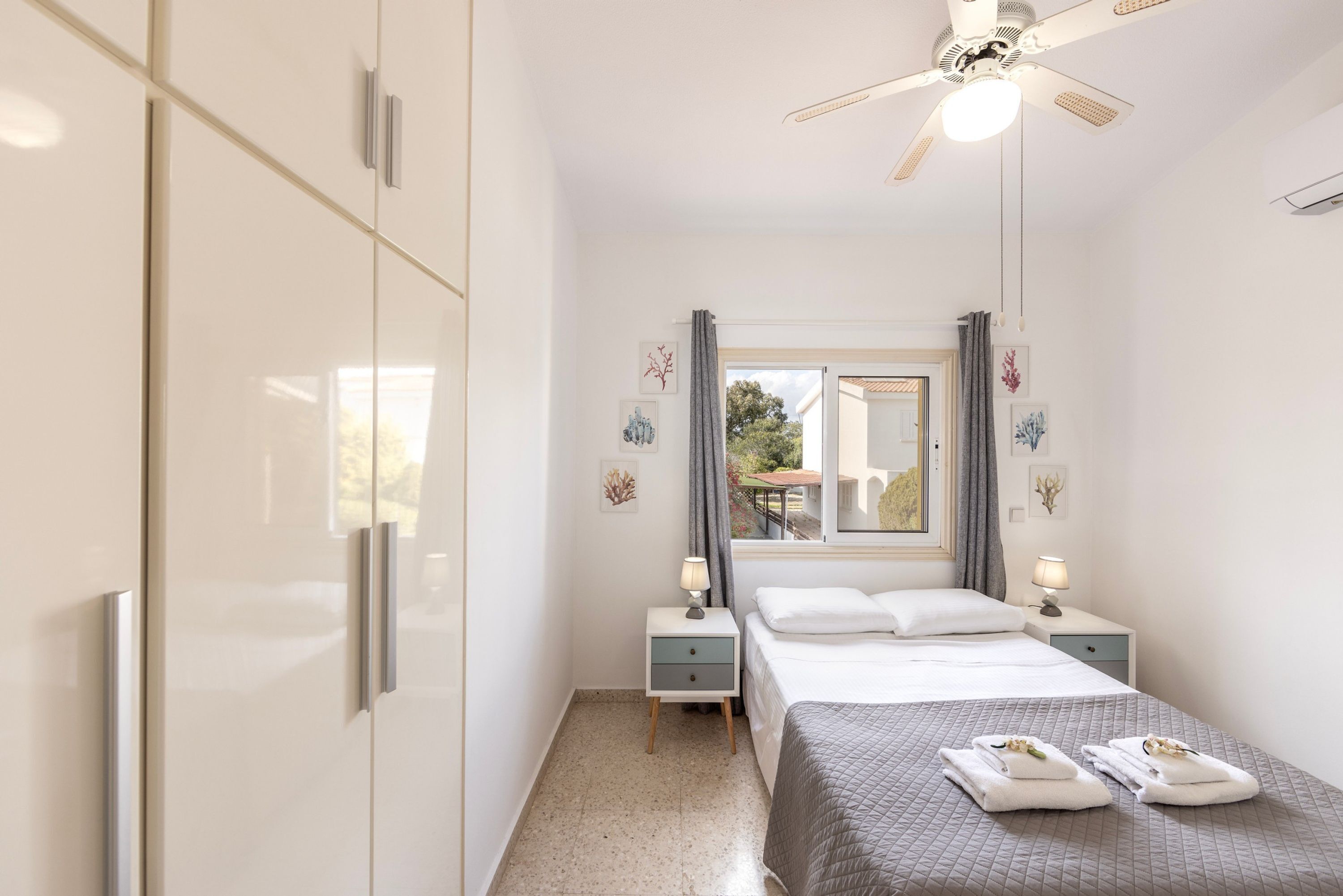 A bedroom with a bed, nightstands, a ceiling fan, and a window with curtains.