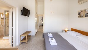 Une chambre d’hôtel avec un lit, un ventilateur de plafond, une télévision et un banc.