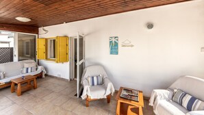 Une pièce chaleureuse avec un plafond en bois, un canapé, un fauteuil et une petite table.