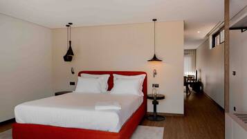 Een moderne hotelkamer met een rood bed, witte beddengoed en twee hanglampen.