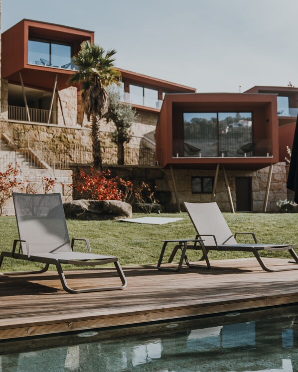 A modern outdoor pool area with two lounge chairs and a stone wall with a staircase. - Quinta de Santo António - Country House & Villas (Marco de Canaveses)