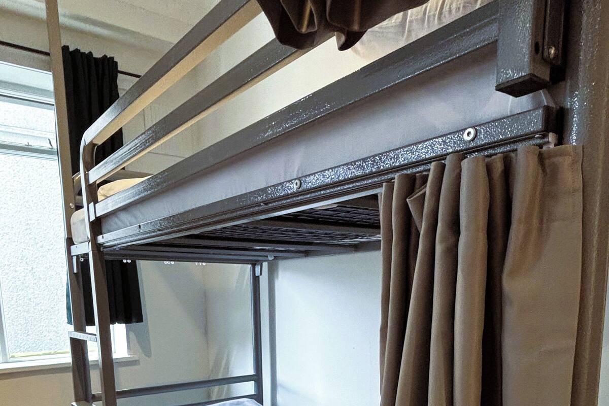 A bunk bed with a mattress, a drawer, and curtains.
