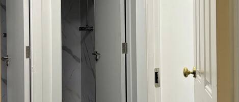 Un couloir avec deux portes ouvertes donnant sur une pièce dont le sol est recouvert de marbre.