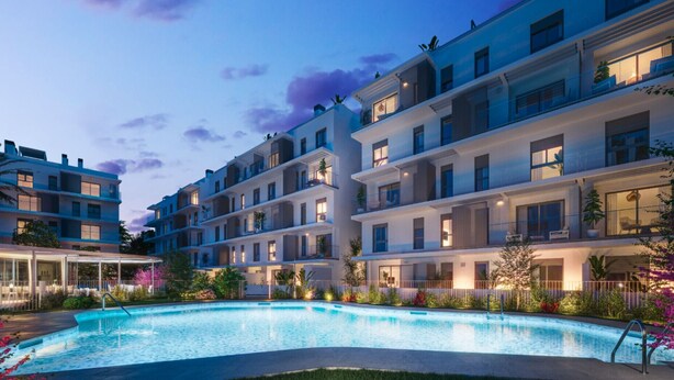 A modern hotel with multiple balconies, a swimming pool, and well-lit outdoor areas.