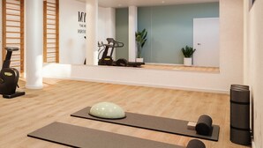 A modern gym with exercise equipment, wooden flooring, and a large mirror.