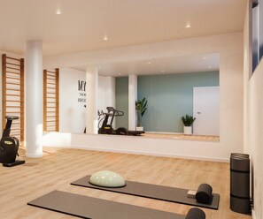 A modern gym with exercise equipment, wooden flooring, and a large mirror.