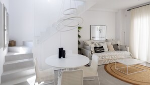 A modern living room with a white sofa, a round coffee table, and a staircase leading to another level.