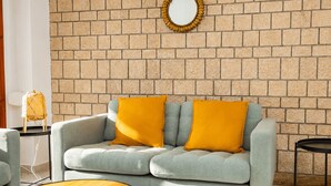 A living room with a brick wall, a sofa with two cushions, a round wooden coffee table, and a small side table with a lamp. - Cullera Beachfront Apartment (Cullera)