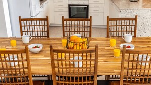 A dining area with a wooden table and chairs, a fruit basket, and breakfast items. - Cullera Beachfront Apartment (Cullera)