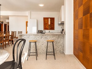 Une cuisine moderne avec un plan de travail en marbre, des chaises en bois et un meuble en bois.