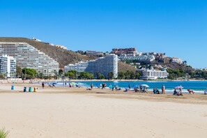 A beach with buildings in the background, clear skies, and people enjoying the beach. - Cullera Beachfront Apartment (Cullera)