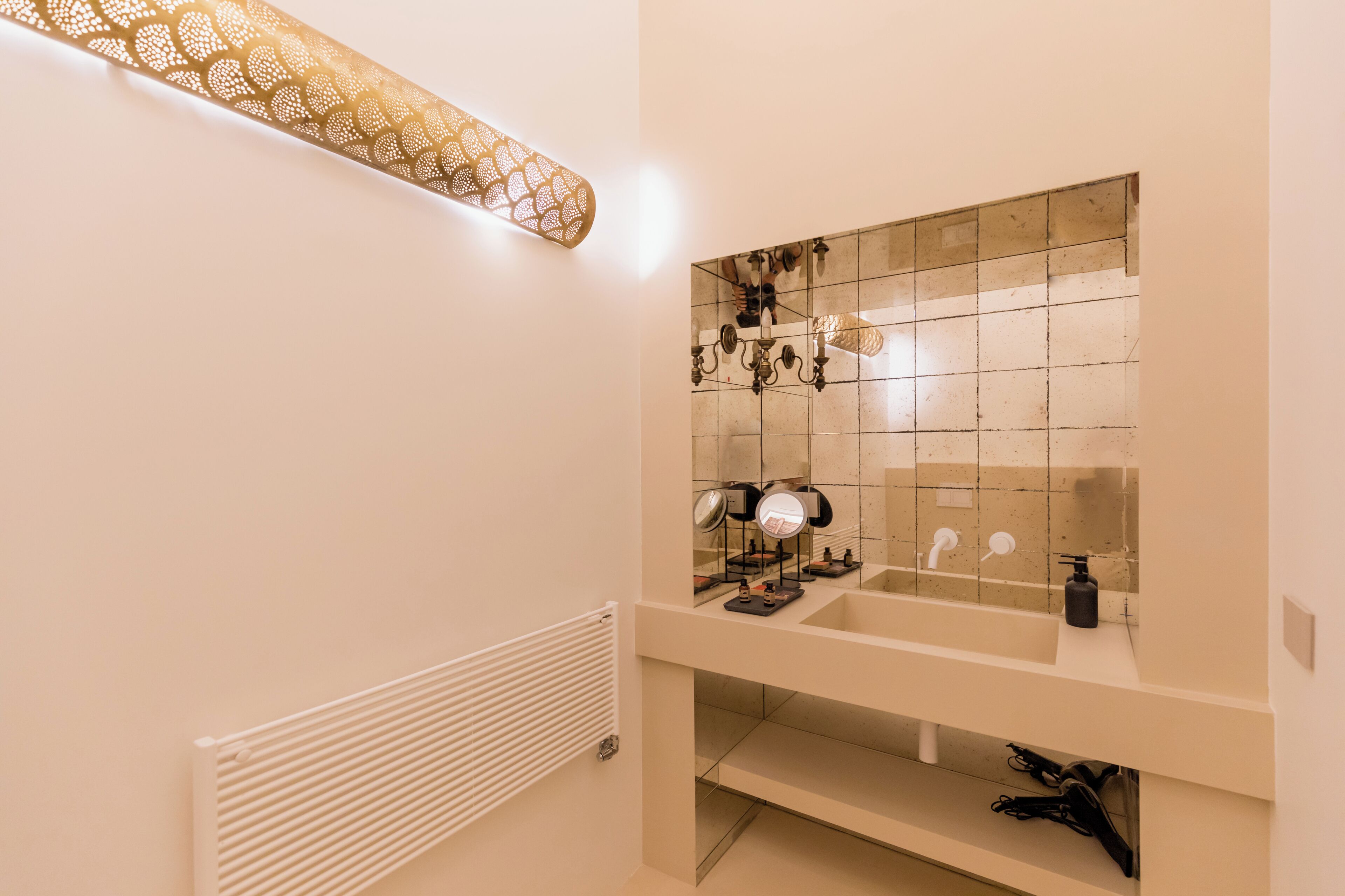 Une salle de bain moderne avec un grand miroir, un lavabo et un radiateur.