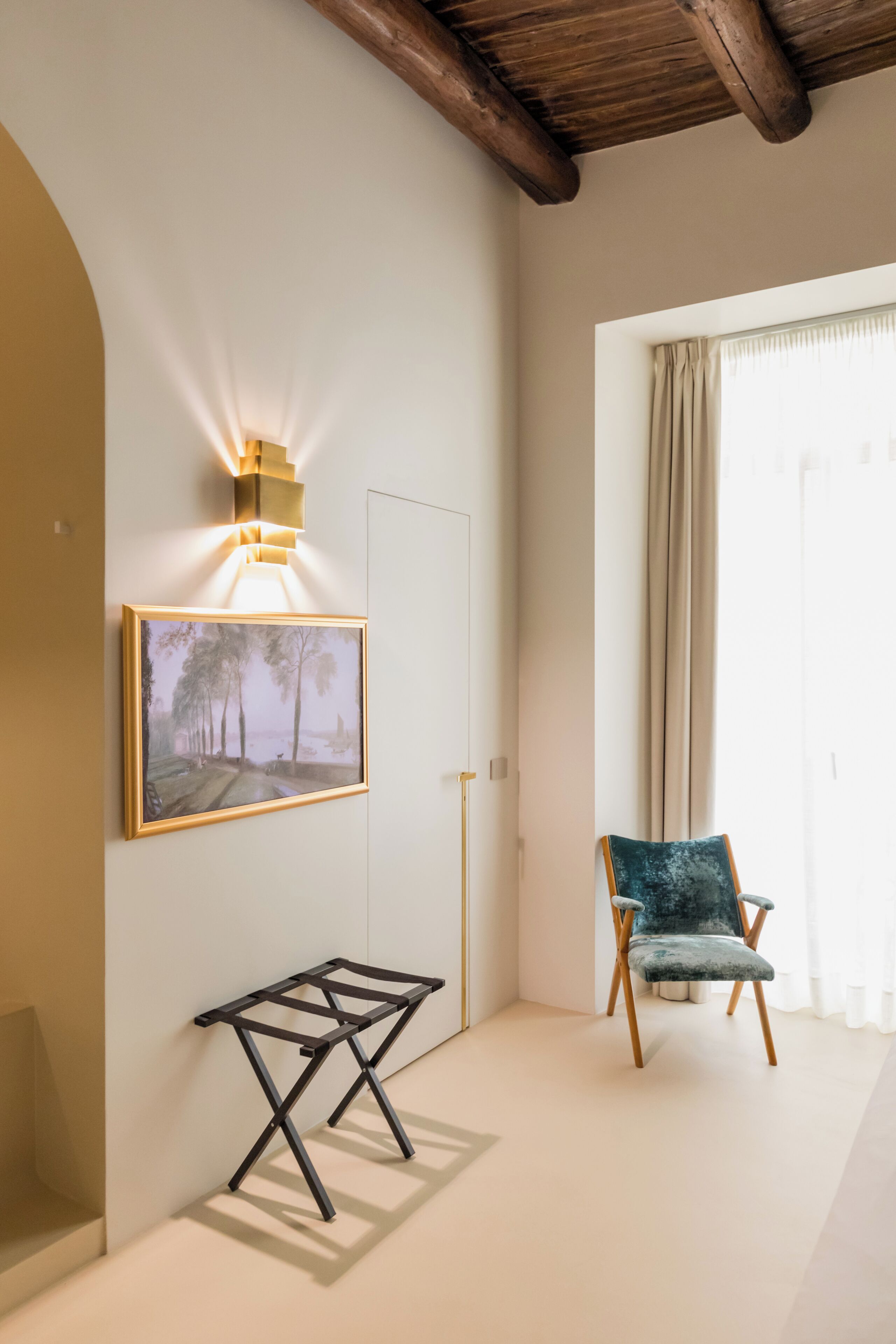 A room with a framed painting, a modern table, a chair, and a ceiling light fixture.