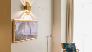 A room with a framed painting, a modern table, a chair, and a ceiling light fixture.