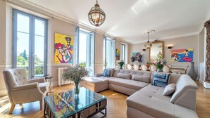 A spacious living room with a large sectional sofa, a glass coffee table, and a dining area with a table and chairs. - Château Les Alouettes (Cannes)