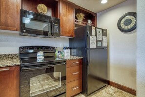A kitchen with a microwave, oven, refrigerator, and a clock on the wall. - Downtown Pigeon Forge | Resort Pool | Pet Friendly | WiFi (Pigeon Forge)