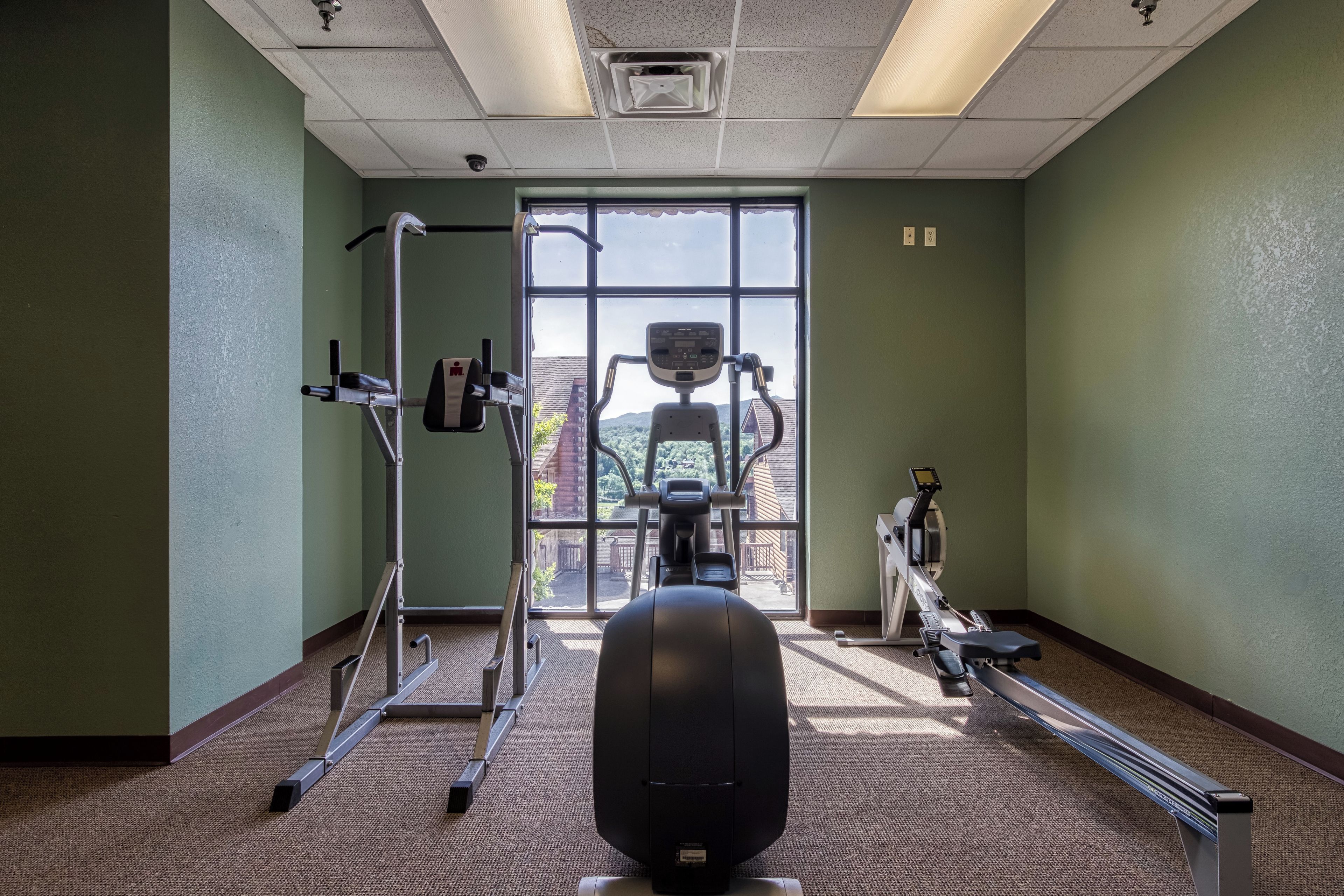 A gym with exercise equipment, a large window, and a view of the outdoors.