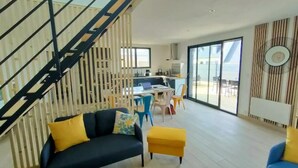 Una sala moderna con una escalera, un comedor y una cocina.